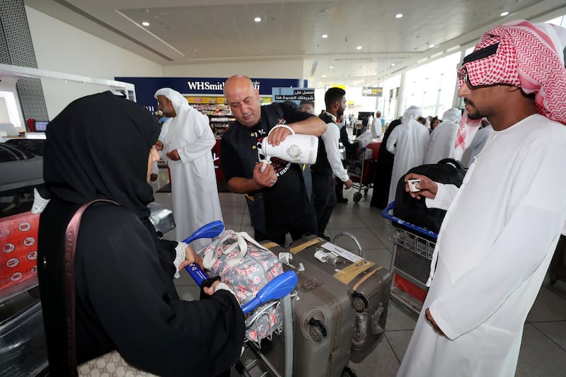 Abu Dhabi, United Arab Emirates - August 15, 2019: Ahmad hands out coffee as people return from the Hajj pilgrimage. The pilgrims will be returning following the Eid Al Adha holiday. Thursday the 15th of August 2019. Abu Dhabi International Airport, Abu Dhabi. Chris Whiteoak / The National