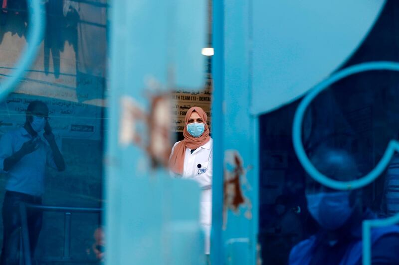 Palestinian UN doctor wearing face mask to limit the spread of Covid-19 stands behind a door at a clinic in Bureij refugee camp in Gaza Strip.  AFP