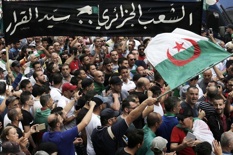 Algerian demonstrators take to the streets in the capital Algiers to protest against the government, in Algeria, Friday, Sept. 13, 2019. Africa's largest country has had no elected president for five months, and the powerful army chief wants to change that after months of protests he sees as a threat. Placard in Arabic that reads, " the Algerian people take their own decision". (AP Photo/Toufik Doudou)