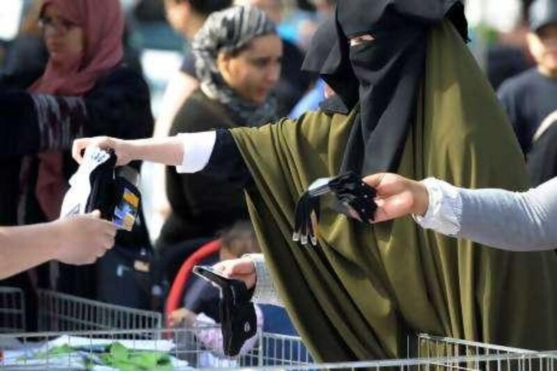 Samira, 36, wearing a niqab, the islamic full veil, buy socks at a market of Venissieux near Lyon, eastern France, on April 22, 2010. French government will pass a law to ban Muslim women from wearing a full-face veil in public, despite a warning from experts that such a law could be unconstitutional, it announced on April 21.      AFP PHOTO / PHILIPPE DESMAZES