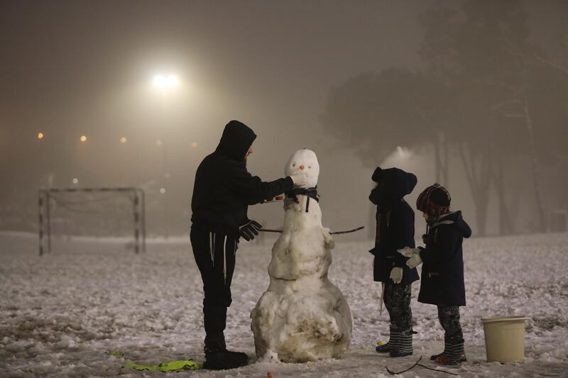 An ultra-orthodox man and his sons build a snowman in Sacher Park in Jerusalem, Israel, 18 February 2021.  EPA