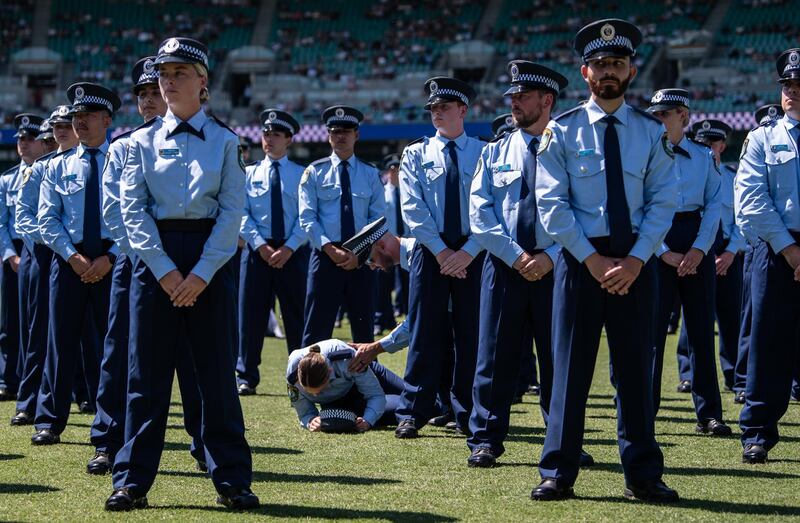 A police officer lies on the ground after collapsing during a police Attestation Parade at the Sydney Cricket Ground in Sydney, Australia.  EPA