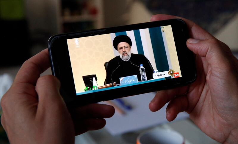 An Iranian woman watches the first presidential candidates TV debate on her phone. EPA