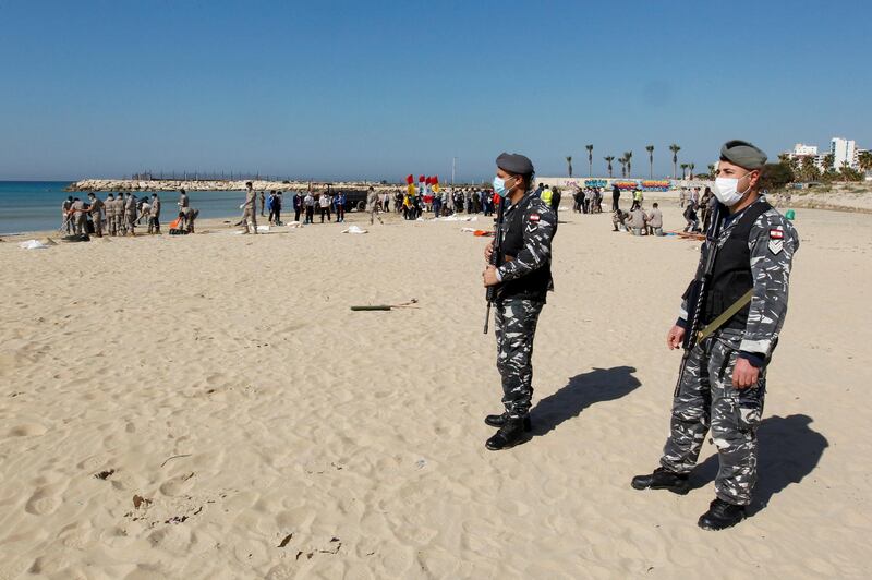 Members of security forces stand guard as volunteers clean a beach after an oil spill in the Mediterranean Sea that washed up at Tyre in southern Lebanon. Reuters