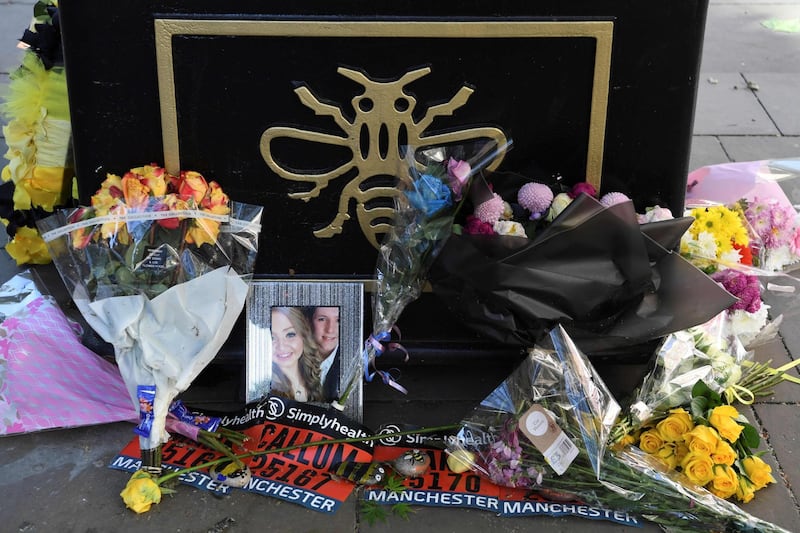 A photograph of victims Liam Curry and Chloe Rutherford is seen amongst floral tributes at the base of a 'tree of hope', planted as a memorial following the Manchester Arena bombing in central Manchester. AFP
