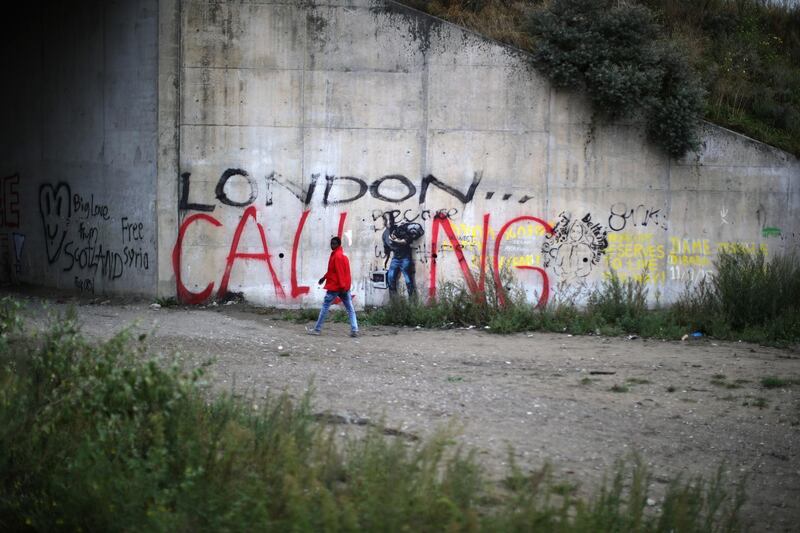 A migrant at the Jungle camp, walks past graffiti on September 5, 2016. Getty Images