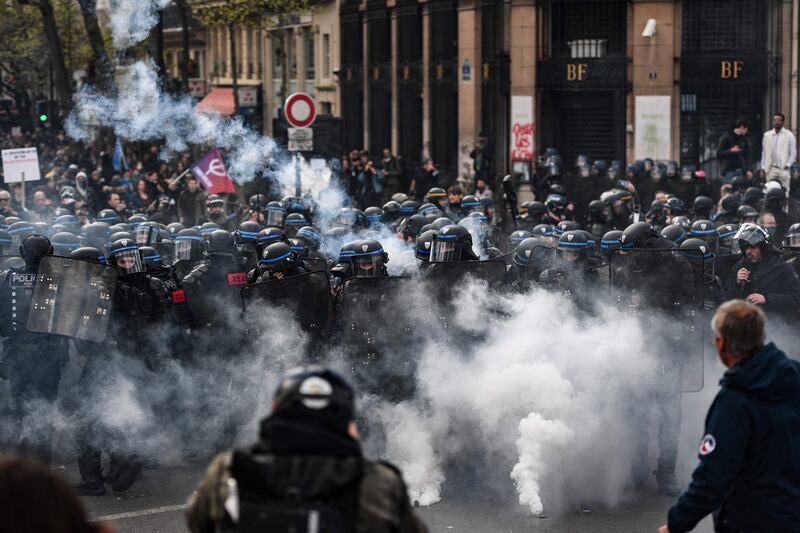 Police stand in formation amid tear gas smoke near the Bank of France. AFP