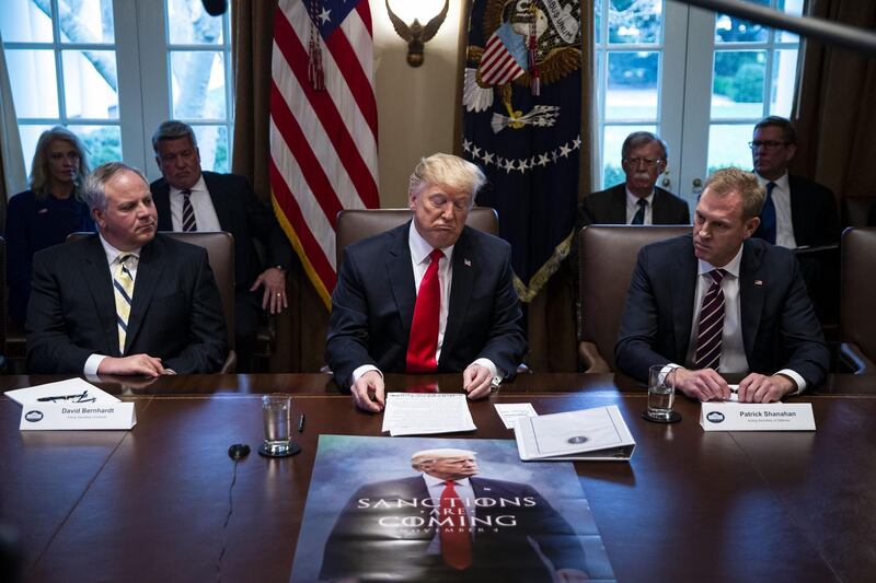 U.S. President Donald Trump, center, pauses while speaking in front of a poster that reads "Sanctions Are Coming" during a meeting in the Cabinet Room of the White House in Washington, D.C., U.S., on on Wednesday, Jan. 2, 2019. Trump insisted the U.S. needs some kind of physical barrier along the frontier with Mexico, just a few hours before a meeting with congressional leaders aimed at breaking a stalemate over border wall funding that’s kept parts of the federal government shut down for 12 days. Photographer: Al Drago/Bloomberg