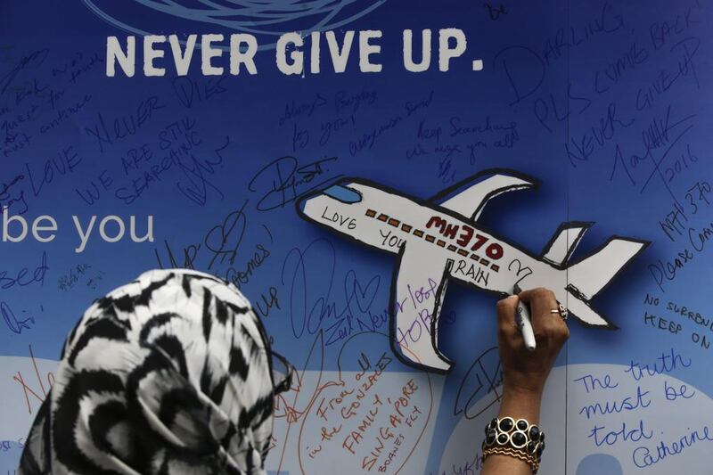 A woman writes messages for the passengers of missing Malaysia Airlines flight MH370 on a banner during a remembrance ceremony to mark the second anniversary of the plane's disappearance, in Kuala Lumpur, Malaysia in March 2016. Fazry Ismail / EPA