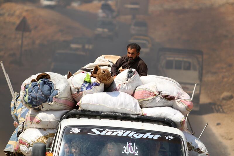 Displaced Syrians who fled from regime raids ride in trucks with their belongings arrive near a camp in Kafr Lusin near the border with Turkey in the northern part of Syria's rebel-held Idlib province.  AFP