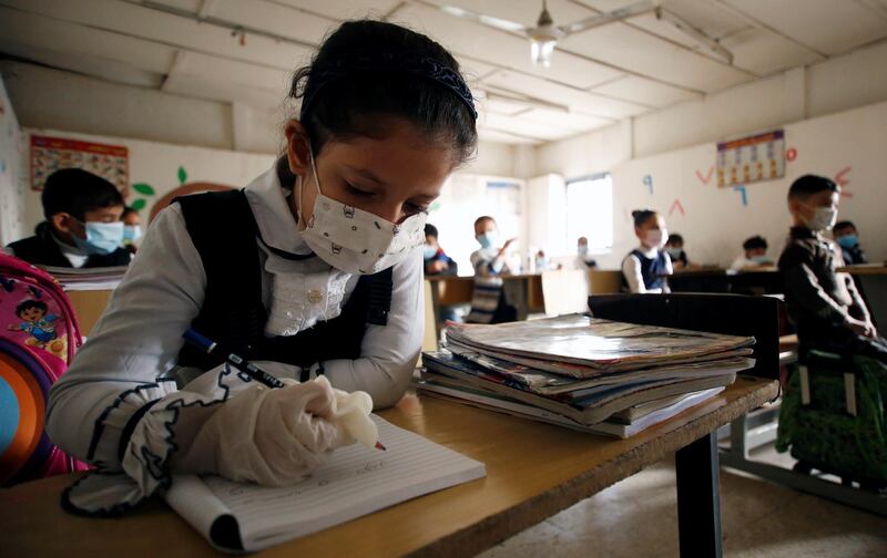 A student writes in her notebook following the reopening of their school, after months of closure due to the spread of the coronavirus disease (COVID-19), in Baghdad, Iraq November 29, 2020. REUTERS/Saba Kareem