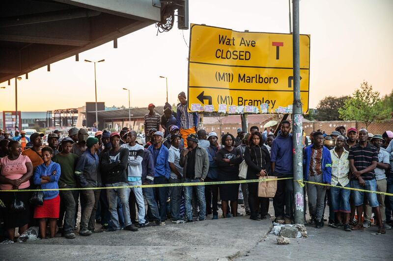 EDITORS NOTE: Graphic content / Residents of Johannesburg's Alexandra township stand behind a police cordon as they gather at the scene where a body of a burned person was found inside a looted shop on September 04, 2019 after South Africa's financial capital was hit by a new wave of anti-foreigner violence.  South African police said they found two charred bodies in a shop in the Johannesburg township of Alexandra, bringing the death toll from xenophobic attacks to seven. / AFP / Michele Spatari

