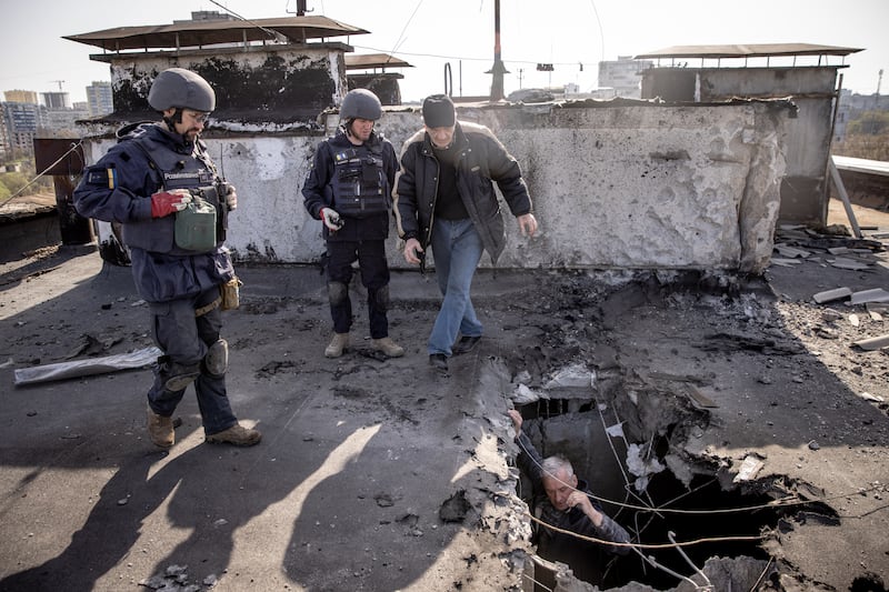 A resident shows deminers the site of an empty rocket that struck the roof of a residential building as they clear the area in Kharkiv, Ukraine. Getty Images
