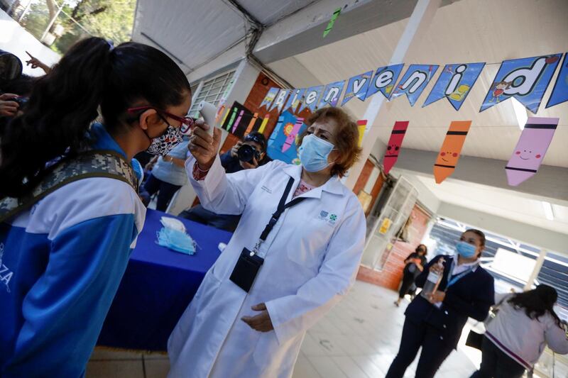 A doctor checks the body temperature of a child arriving at the Ignacio Zaragoza elementary school as Mexico City's authorities resumed in-person classes. Reuters