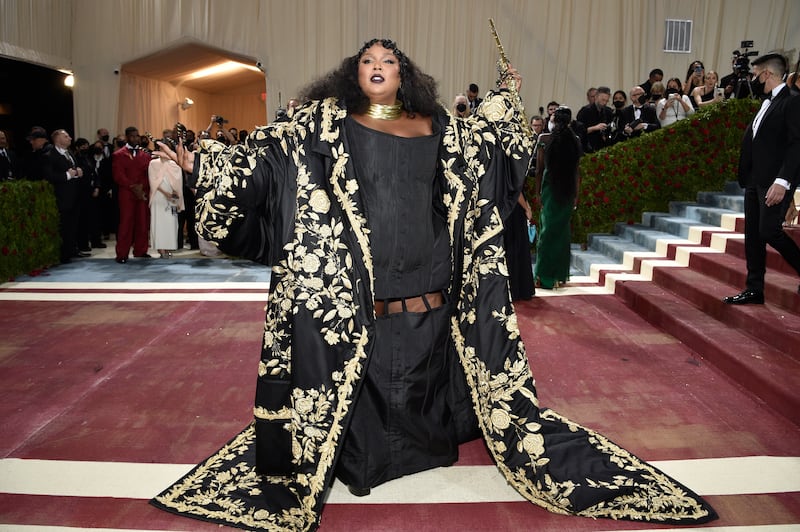 Musician Lizzo wearing a black Thom Browne gown with gold detail. AP Photo