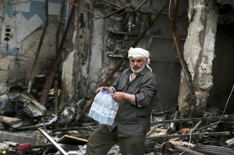A man carries water bottles in an area of Idlib damaged by shelling from forces loyal to Bashar Al Assad after rebels took control of the city. Mahmoud Hebbo / Reuters / March 29, 2015