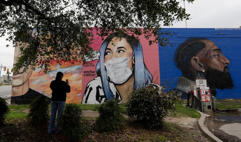 A woman photographs a mural of Cardi B that was updated by the artist to include a face mask to reflect the coronavirus pandemic, in San Antonio. AP Photo