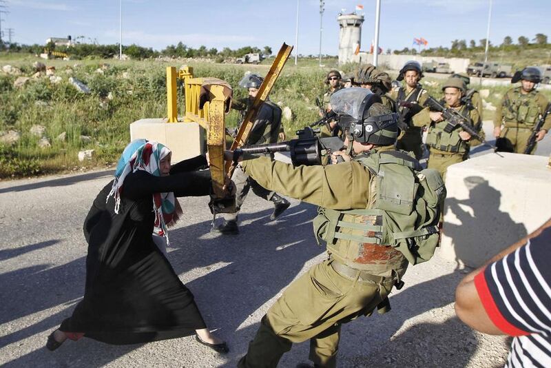 A Palestinian woman scuffles with an Israeli soldier as she tries to open a gate leading to the entrance of Nabi Saleh village, near the West Bank city of Ramallah. Mohamad Torokman / Reuters