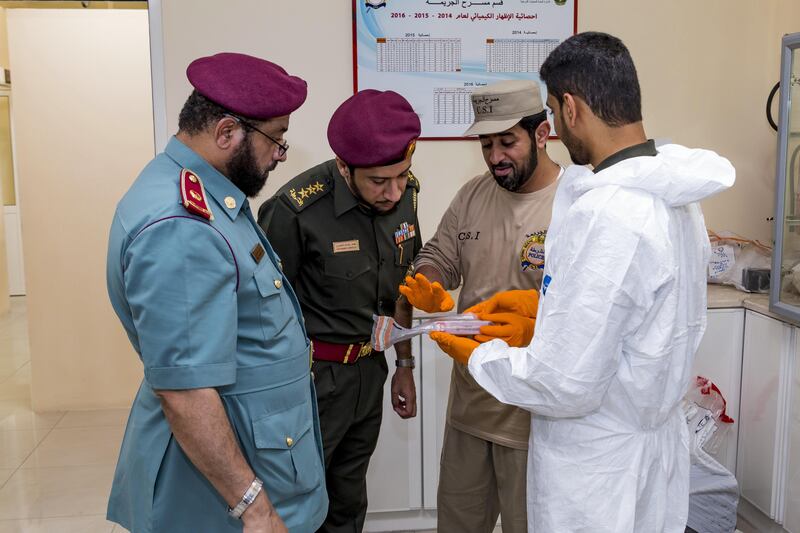 Ajman, UAE - September 05, 2017 - Mohd Hussain Waheedi and Ali Saif Al Shamsi of the Ajman Police Crime Scenes Investigative Unit discuss new evidence with Police Chief Abdalla Yousif Mohd S. Alawadi and officer Mohd Abdulla - Navin Khianey for The National
