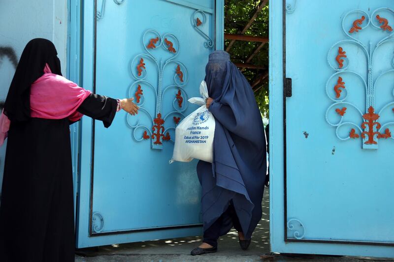 An Afghan woman carries free food donated by Muslim Hands, a not-for-profit organisation, during the last days of Ramadan in Kabul, Afghanistan. AP Photo