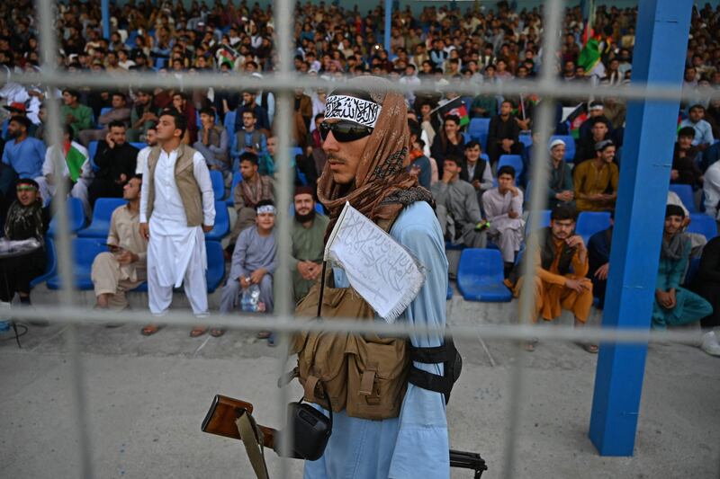 A Taliban fighter keeps vigil as spectators watch the Twenty20 cricket trial match being played between two Afghan teams at the Kabul International Cricket Stadium on September 3, 2021.  AFP