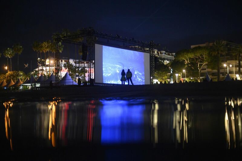 TOPSHOT - People attend the 25th anniversary of the film "La Cite de la Peur (Fear City) at the Cinema de la plage on the sidelines of the 72nd edition of the Cannes Film Festival in Cannes, southern France, on May 16, 2019. / AFP / Olivier MORIN
