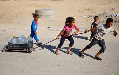 Palestinian children pull water containers as people flee Rafah after Israeli forces launched a ground and air operation in the eastern part of the city. Reuters