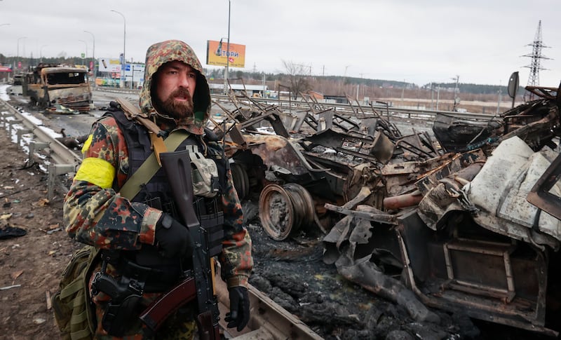 An armed man stands by the remains of a Russian military vehicle in Bucha. AP