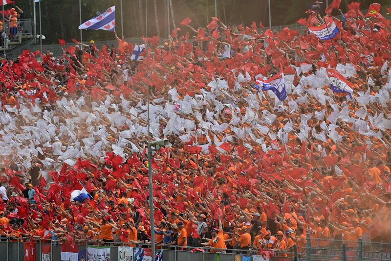 Spectators and supporters of Red Bull's Dutch driver Max Verstappen wave flags at the Red Bull Ring.