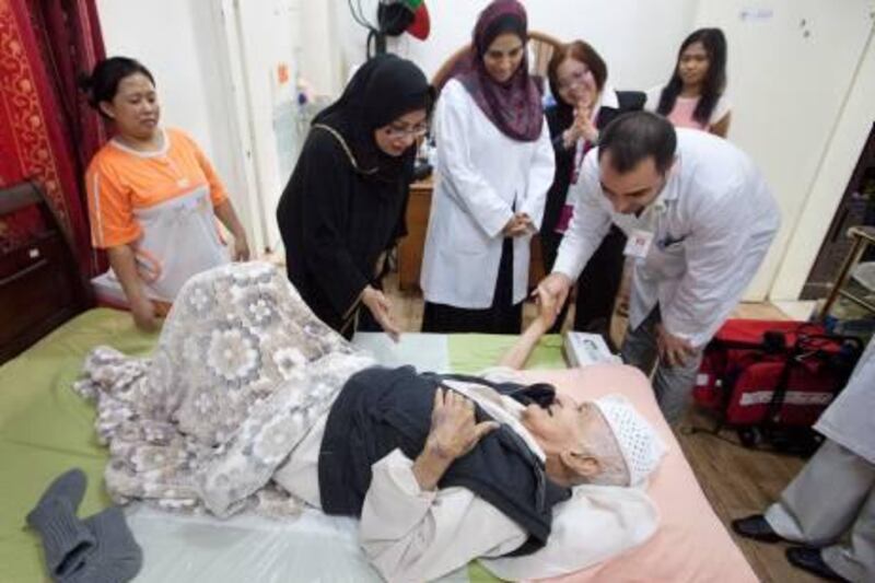 UAE - Dubai - Mar 04 - 2012: Sayed Al Hashemi (below) surrounded by his doughter Maryam al Hashemi (second L to R) shake hands with Phsiotheraphist Iftikhar Hussain Shalla  from Nad Al Hamar Health Center part of Dubai Health Authority, at his apartment in Al Rashadiya.  ( Jaime Puebla - The National Newspaper )