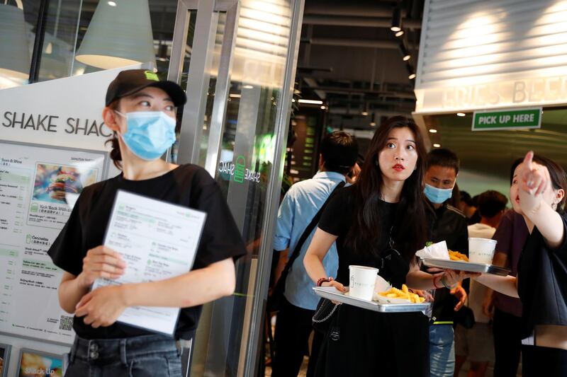 A woman carries her food on the opening day of the first Beijing outlet of the US fast food chain Shake Shack after an outbreak of the Covid-19 in Beijing, China. Reuters