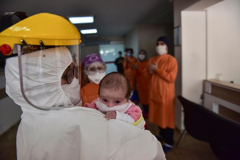 Staff applaud as a nurse, wearing a face mask and a shield to protect against coronavirus, carries baby Amine Tepe out of intensive care unit following a week's treatment, at an Istanbul hospital. Tepe was found to have coronavirus 37 days after her birth, contracting the virus from her parents, according to doctors. The baby has been moved to a hospital ward. AP