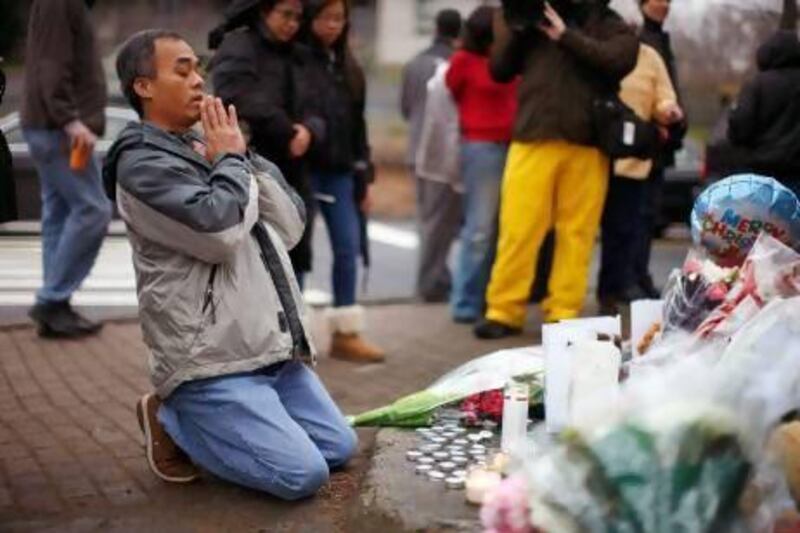 A man prays at a memorial near Sandy Hook Elementary School in Newtown, Connecticut following Friday’s shooting.