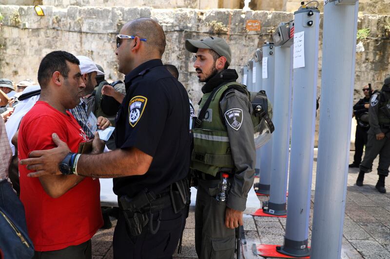 An Israeli police officer checks the identity of a Palestinian man next to newly installed metal detectors at an entrance to the compound known to Muslims as Noble Sanctuary and to Jews as Temple Mount, in Jerusalem's Old City. Ammar Awad / Reuters