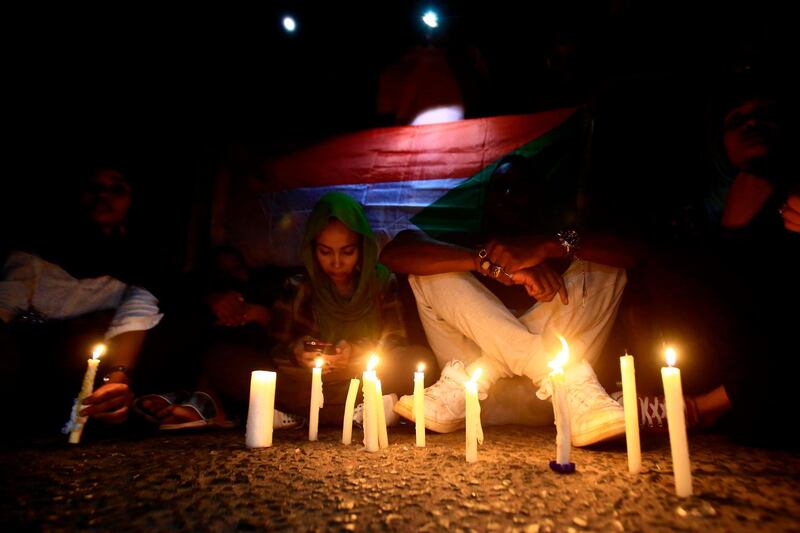TOPSHOT - Sudanese protesters take part in a vigil in the capital Khartoum to mourn dozens of demonstrators killed last month in a brutal raid on a Khartoum sit-in, on July 13, 2019.  Crowds of protesters were violently dispersed by men in military fatigues in a pre-dawn raid on a protest site outside army headquarters on June 3. / AFP / ASHRAF SHAZLY
