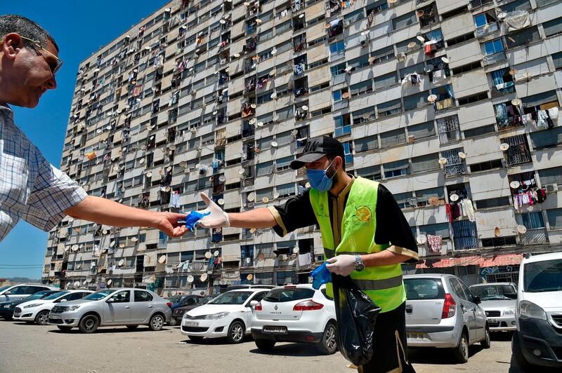 An Algerian man receives a mask distributed by volunteers from the civil society, in a neighbourhood of the capital Algiers.  AFP