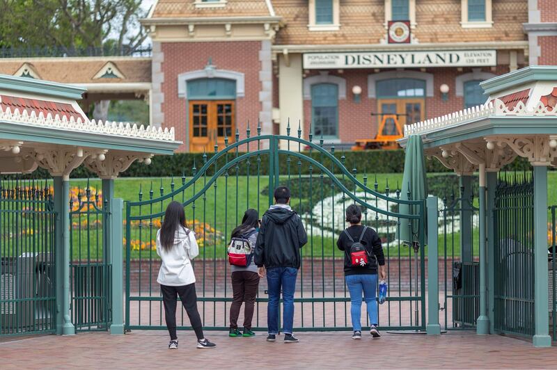 People stand outside the gates of Disneyland Park on the first day of the closure of Disneyland and Disney California Adventure theme parks as fear of the spread of coronavirus continue, in Anaheim, California, on March 14, 2020. - The World Health Organization said March 13, 2020 it was not yet possible to say when the COVID-19 pandemic, which has killed more than 5,000 people worldwide, will peak. "It's impossible for us to say when this will peak globally," Maria Van Kerkhove, who heads the WHO's emerging diseases unit, told a virtual press conference, adding that "we hope that it is sooner rather than later". (Photo by DAVID MCNEW / AFP)