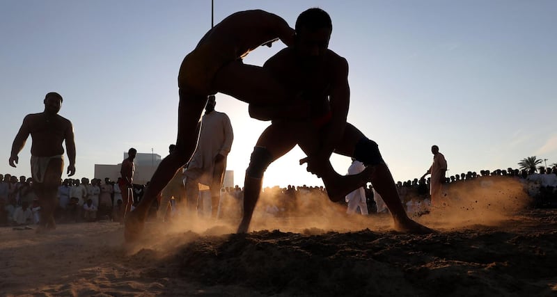 (FILES) In this file photo taken on March 16, 2018 Pakistani immigrant workers in the United Arab Emirates take part in a Kushti competition in Dubai. 
Kushti is popular in India, Pakistan and Bangladesh and was developed in the Mughal era by combining native 'malla-yuddha' wrestling with Persian 'pahlavani'. Every Friday evening in Dubai's bustling Deira district, a sandy lot is transformed into the ring of champions. It is kushti wrestling night and Kala Pehlwan is ready to fight. / AFP PHOTO / KARIM SAHIB