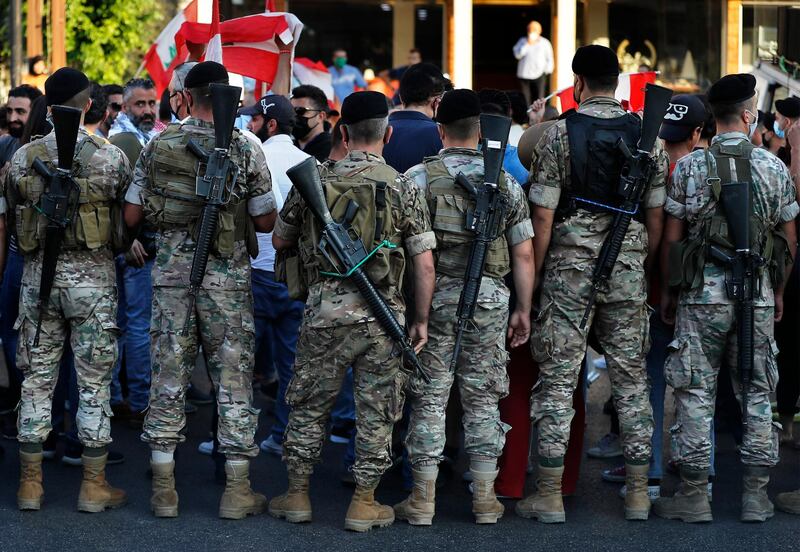 Lebanese army soldier stand in front of anti-government protesters, as they try to get them to unblock a main highway that links Beirut with north Lebanon during a protest against rising prices and worsening economic and financial conditions, in Zalka, north of Beirut, Lebanon. AP Photo