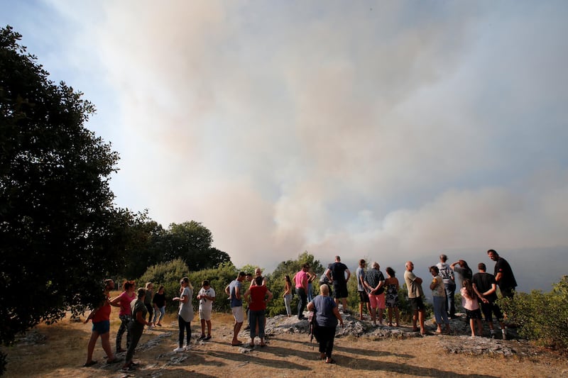 People look at smoke that fills the sky from a forest fire near Seillons, in the Var department, France, July 25, 2017.  REUTERS/Jean-Paul Pelissier