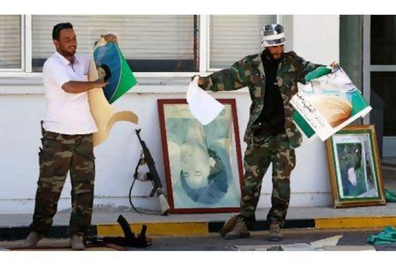 Rebel fighters destroy posters of Libyan leader Muammar Qaddafi which were found in the administrative center after rebels seized control of the Zawiyah oil refinery Thursday.