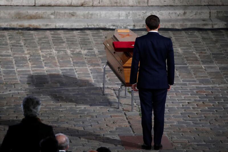 French President Emmanuel Macron pays his respects by the coffin of slain teacher Samuel Paty in the courtyard of the Sorbonne university during a national memorial event, in Paris, France October 21, 2020. REUTERS