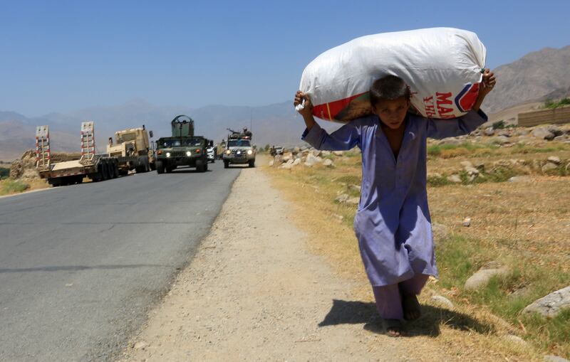 Afghan National Army soldiers patrol the area near their checkpoint recaptured from the Taliban, as a boy carries a sack, in the Alishing district of Laghman province, Afghanistan July 8. Reuters