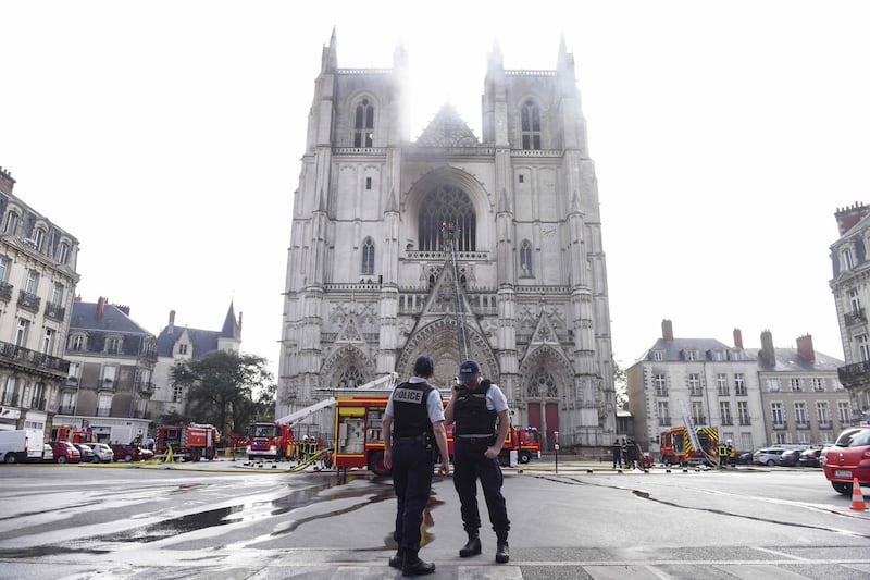 French Police officers stand ready as firefighters work to put out a fire at the Saint-Pierre-et-Saint-Paul cathedral in Nantes, western France. AFP