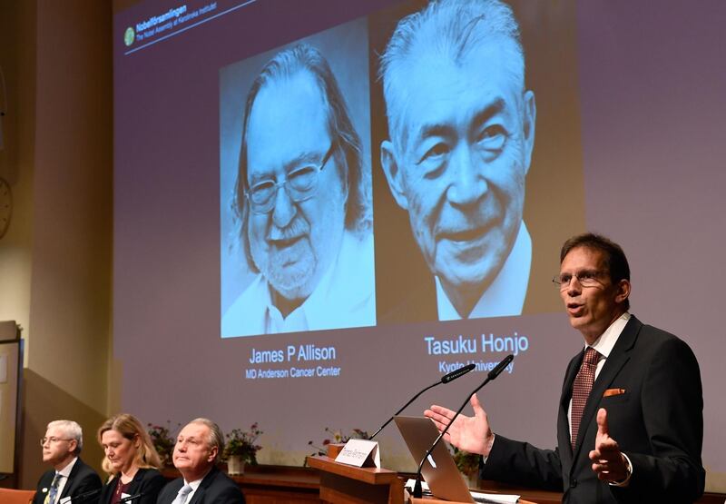 Secretary of the Nobel Committee for Physiology or Medicine, Thomas Perlmann (R) stands next to a screen displaying portraits of James P Allison (L) and Tasuku Honjo during the announcement of the winners of the 2018 Nobel Prize in Physiology or Medicine, during a press conference at the Karolinska Institute in Stockholm, Sweden, on October 1, 2018. James P Allison of US and Tasuku Honjo of Japan won Nobel Medicine Prize for their achievements in cancer treatment. / AFP / Jonathan NACKSTRAND
