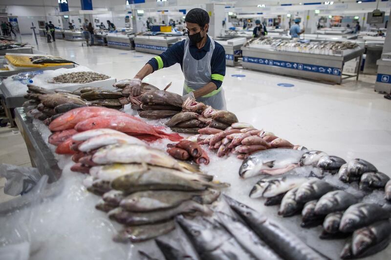 A seller wearing a protective mask at the fish market in Dubai. The Dubai authorities reopened some fish, meat and vegetables markets to the public after they were closed weeks ago to limit spread of the covid-19 coronavirus.  EPA