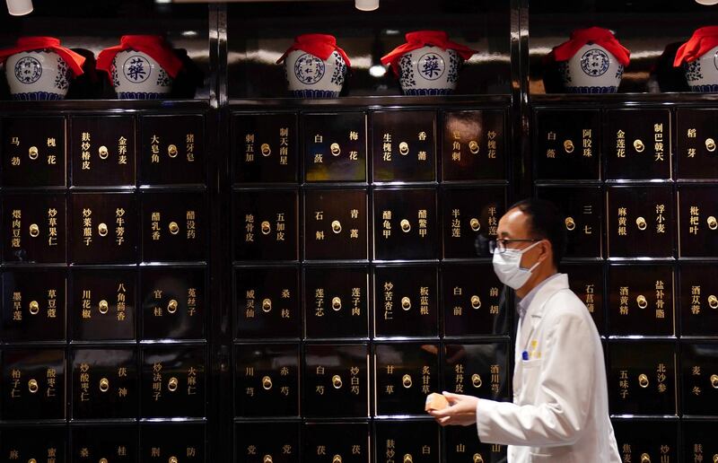 A staff walks past cabinets for herbs at Zhima Health store, a cafe and healthcare retail shop owned by the traditional Chinese medicine brand Tongrentang, in Beijing, China. Reuters