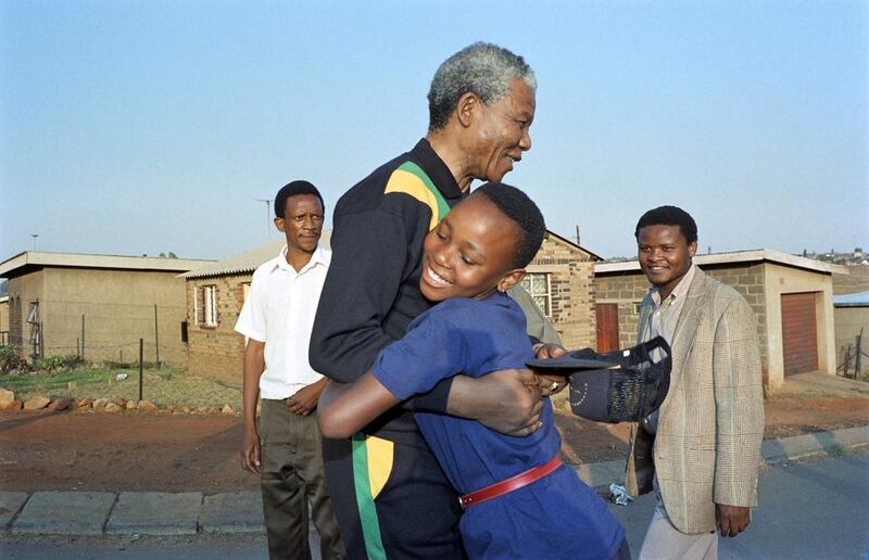 October 4, 1990, Mandela hugs a young Sowetan girl during his visit to the township near Johannesburg.