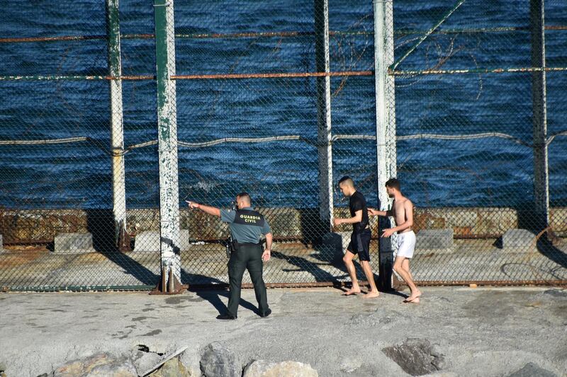 Two migrants are met by a Spanish civil guard in Ceuta. Reuters