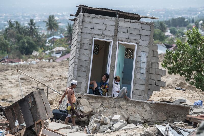 People rest in what was a toilet block in an area of Palu that was completely destroyed by the earthquake and tsunami. Getty Images